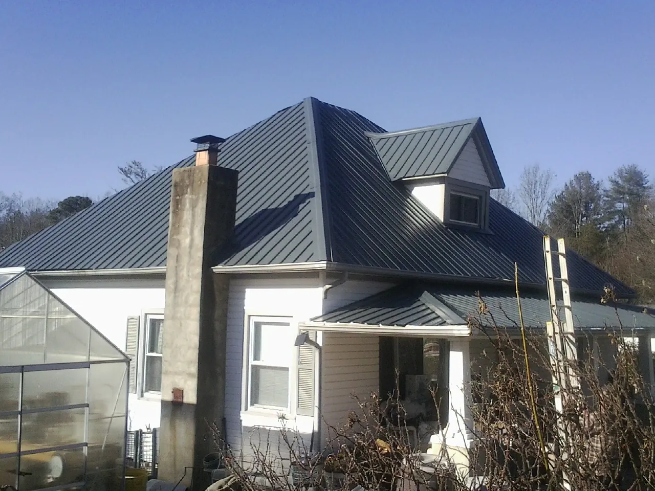 Dark blue standing seam metal roof on a white farmhouse with dormer — Slate & Tile Roof Repair by Roofing Brothers in Willmar