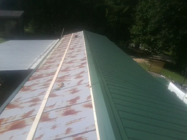 Old rusted panels beside newly installed green metal roofing — Wind Damage Roof Repair by Roofing Brothers in Willmar