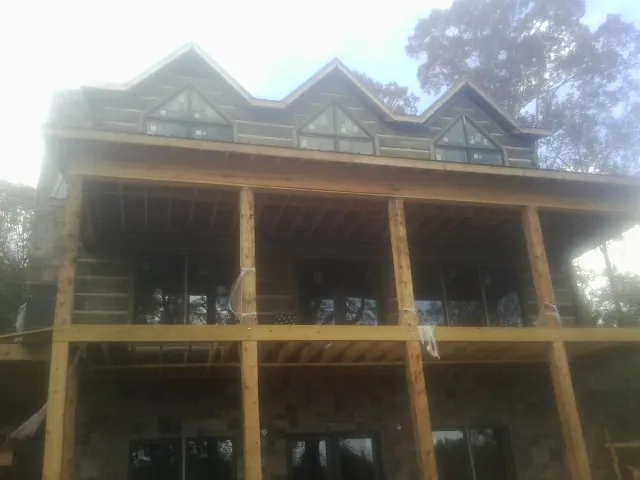 Dormers and porch framing on a large log home under construction — Roof Coating work by our crew in Willmar