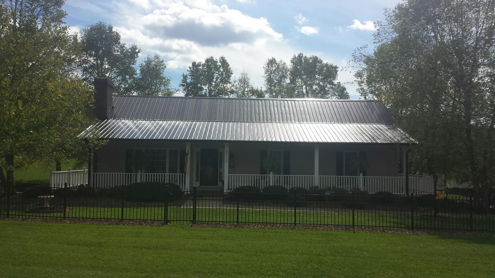 Gray metal roof on a brick ranch with a full width front porch — Gutter Guard Installation work by our crew in Willmar